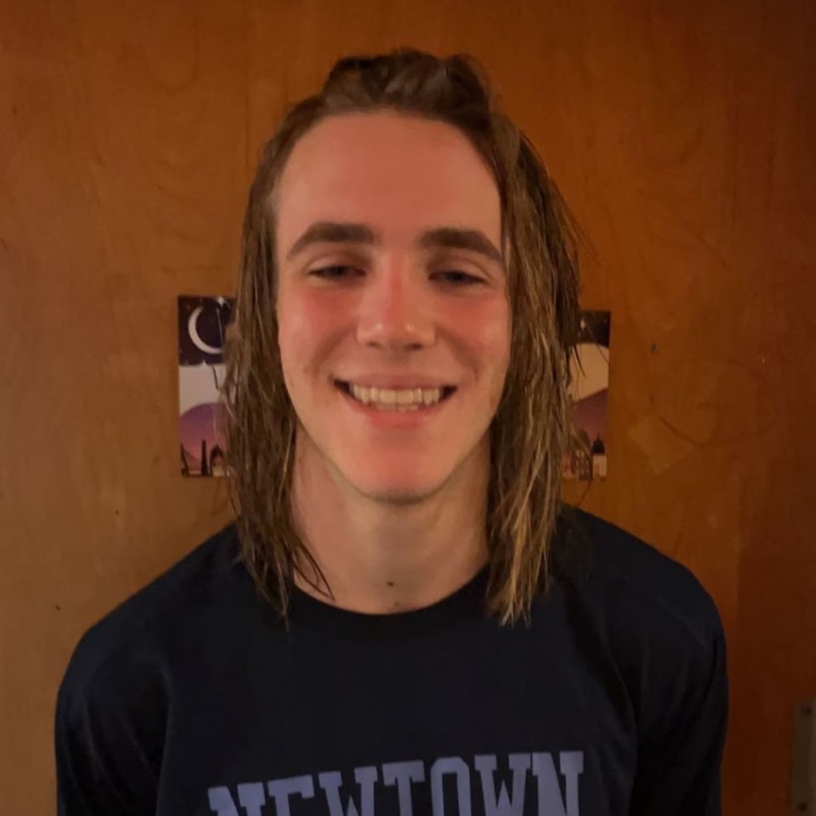 A young man with long hair smiles at the camera.